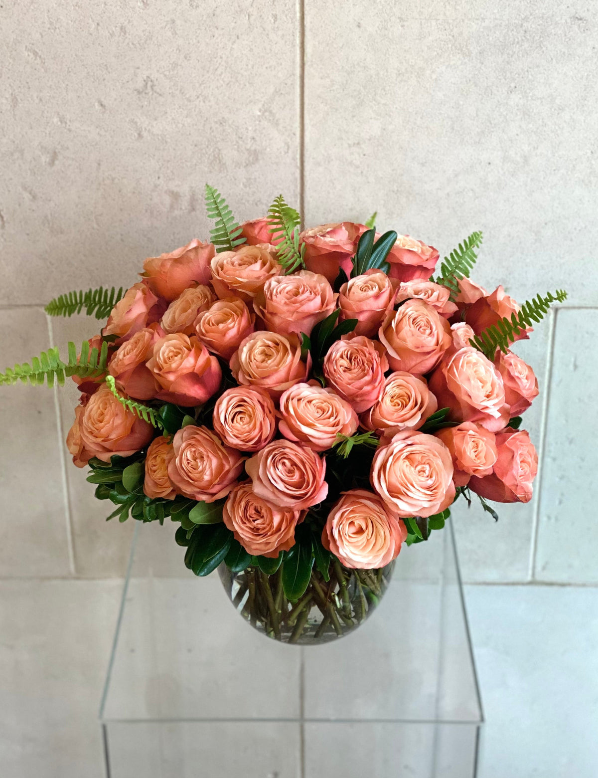 Kahala rose arrangement with peach and blush roses, fresh greenery, and a clear glass vase.