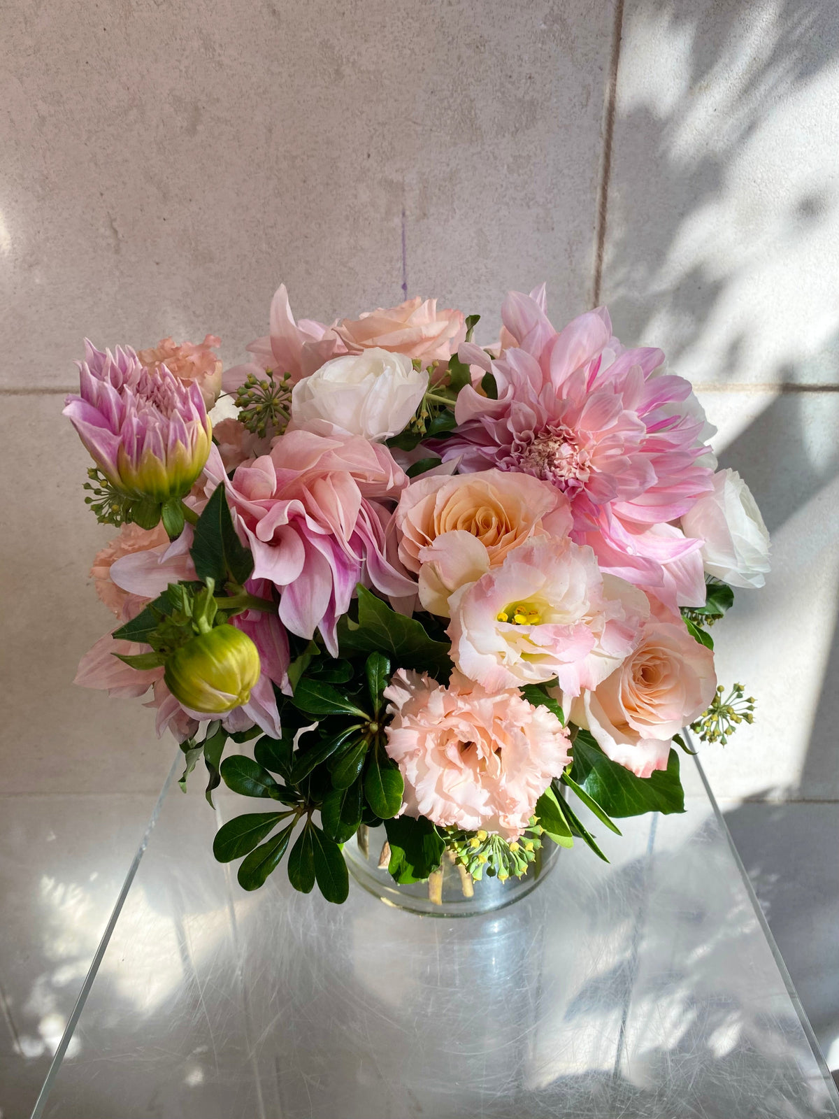 Soft pink floral arrangement with blush roses, pink dahlias, seasonal blooms, and fresh greenery.