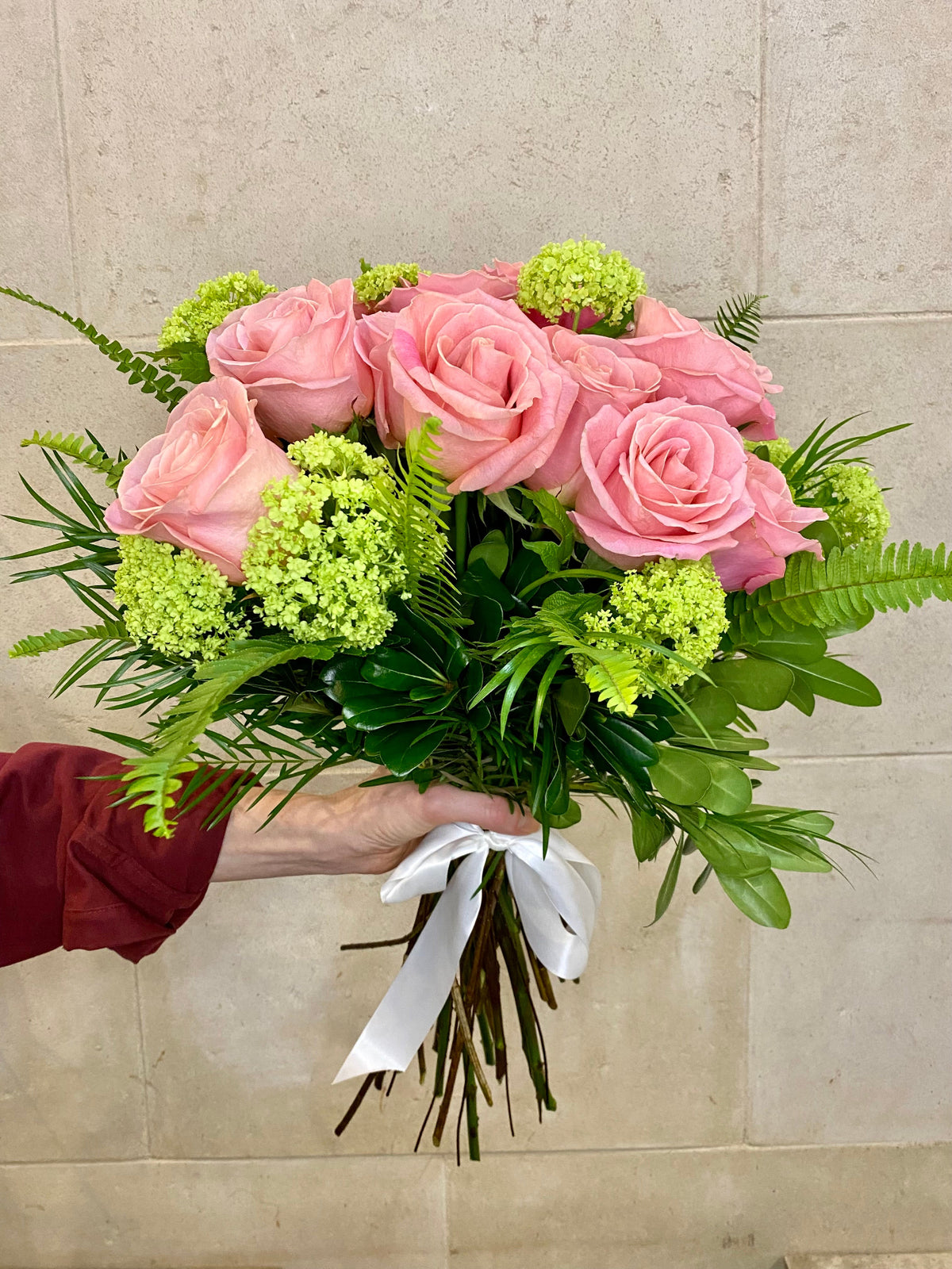 Dozen roses with seasonal accent flowers and fresh greenery, available as a hand-tied bouquet or vase arrangement.