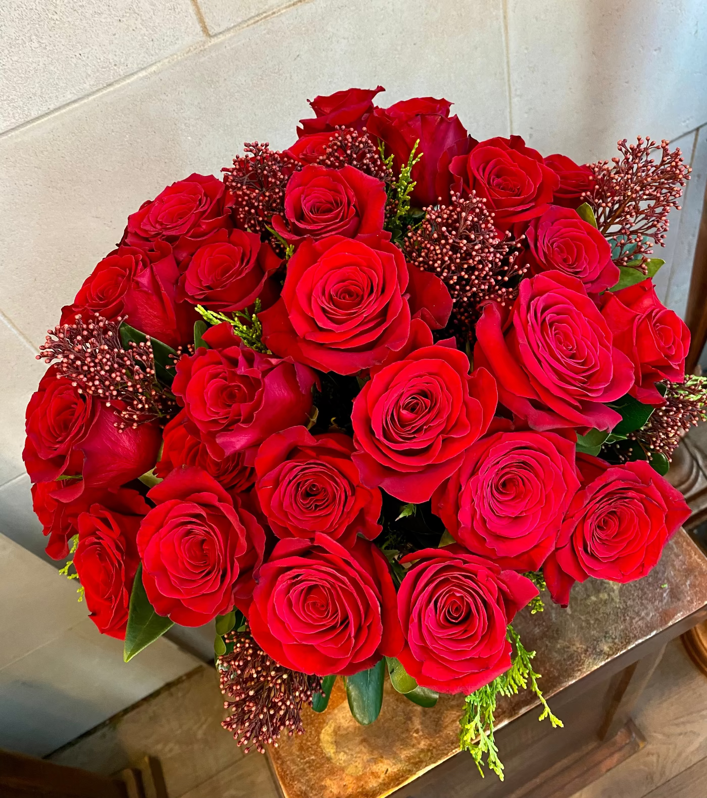 Red rose vase arrangement with premium greenery and seasonal accent flowers.