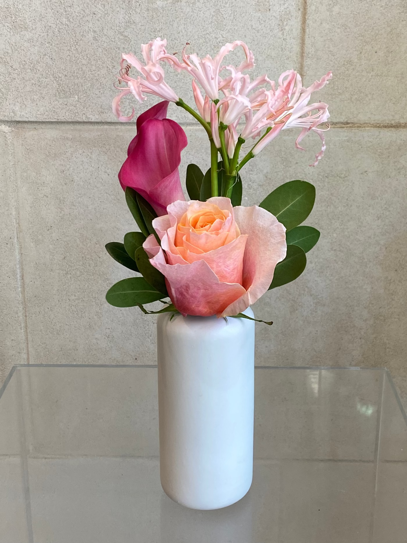 Set of three white ceramic bud vases with seasonal flowers in soft pink and lavender tones