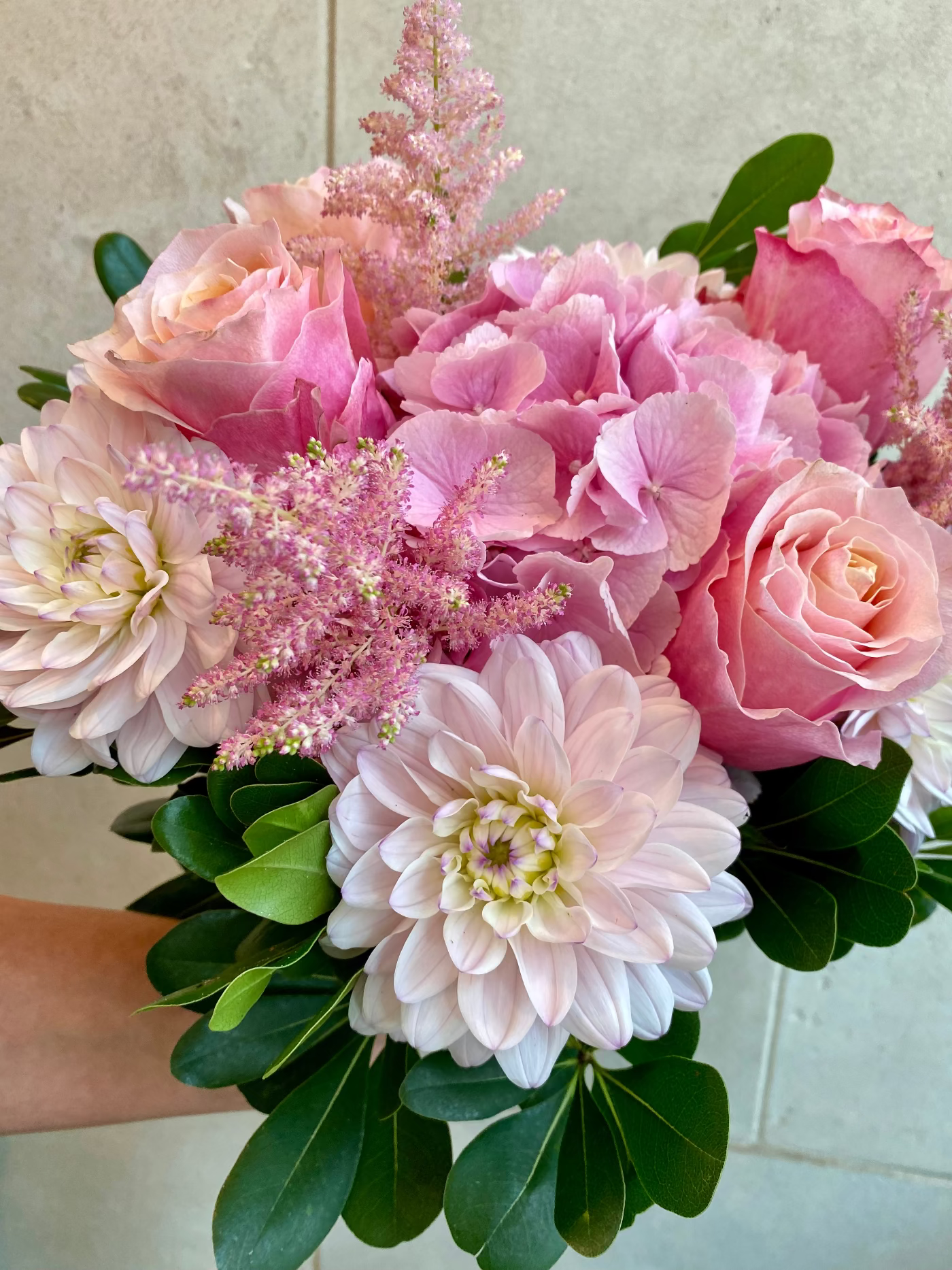 Hand-tied bouquet with pink hydrangeas, blush roses, dahlias, astilbe, and seasonal greenery.