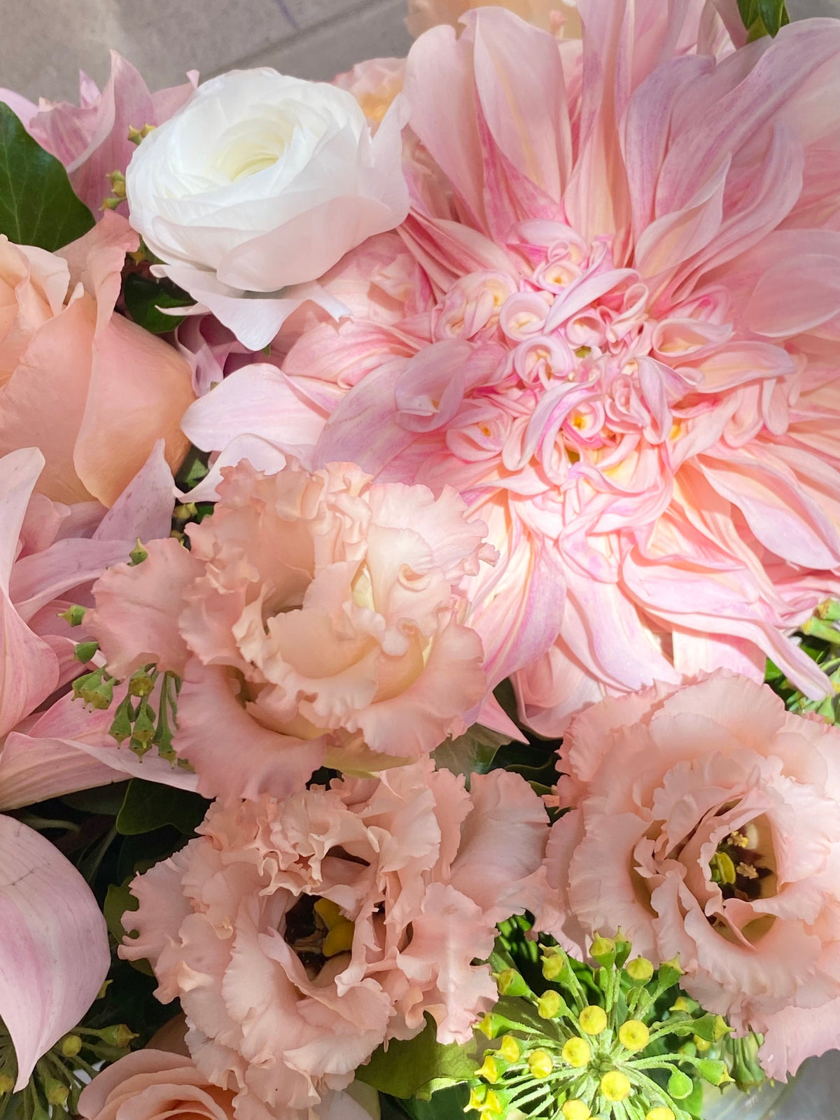 Soft pink floral arrangement with blush roses, pink dahlias, seasonal blooms, and fresh greenery.